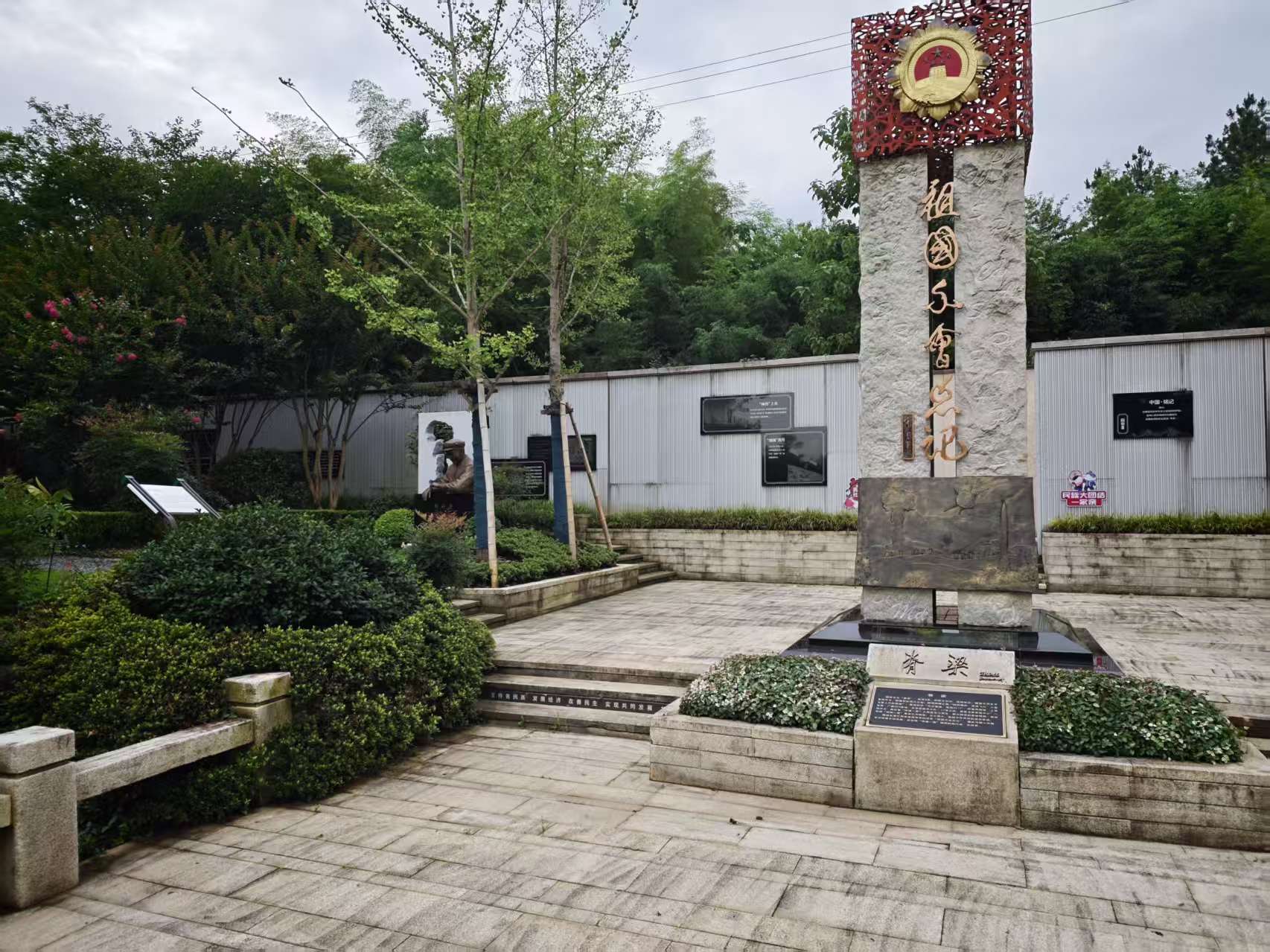 立柱式纪念景观、石铺平台与后方展示墙