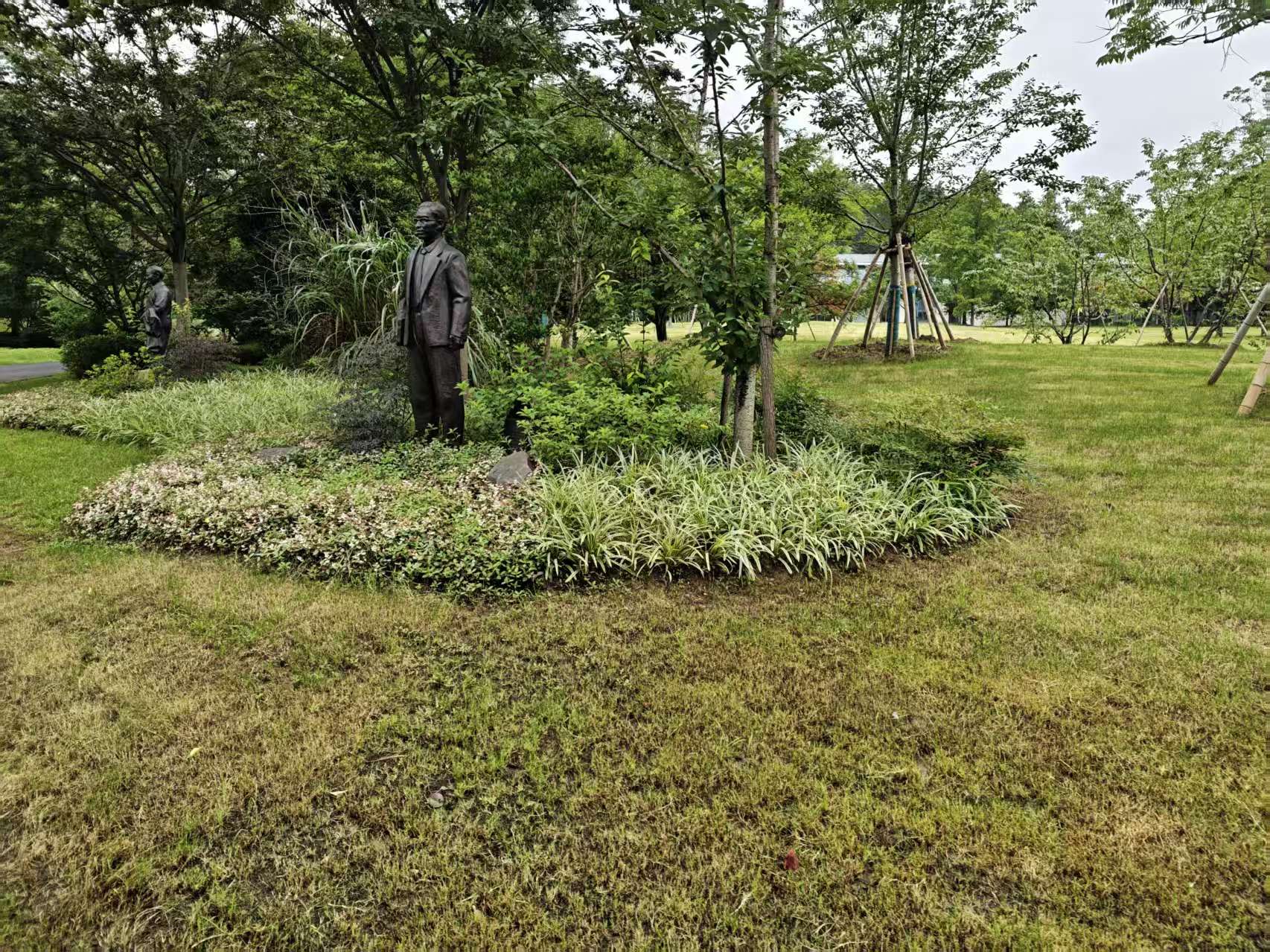 林荫与地被植物间的立姿人物雕塑